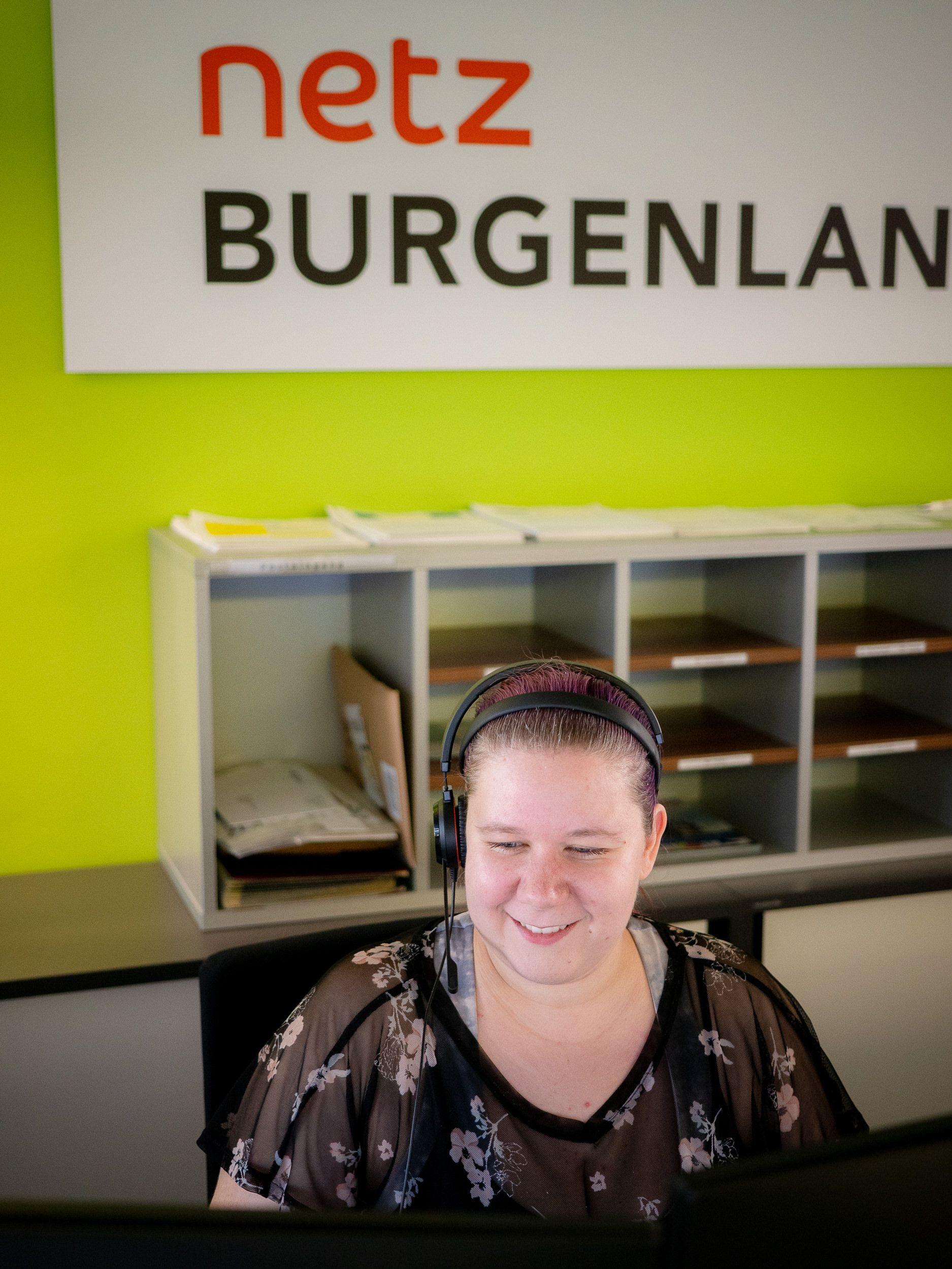 Eine Mitarbeiterin von Netz Burgenland arbeitet lächelnd an einem Computer.