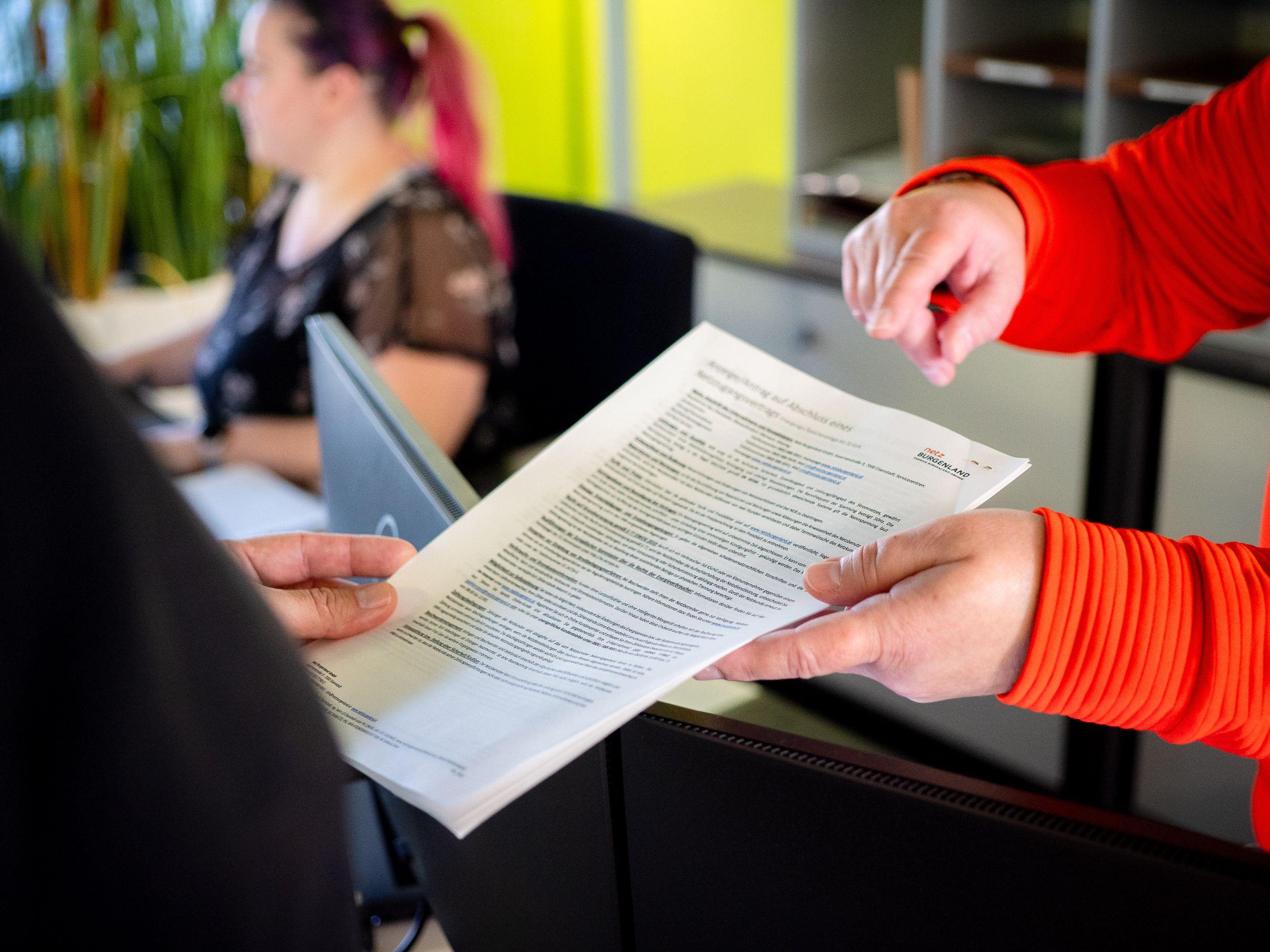 Büroangestellte betrachtet ein Dokument, während ein Kollege darauf zeigt