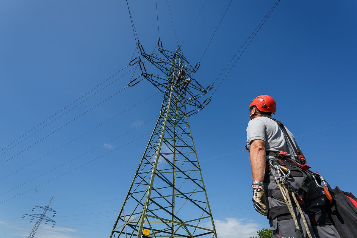 Elektriker arbeitet mit Sicherheitsausrüstung an einer Hochspannungsleitung