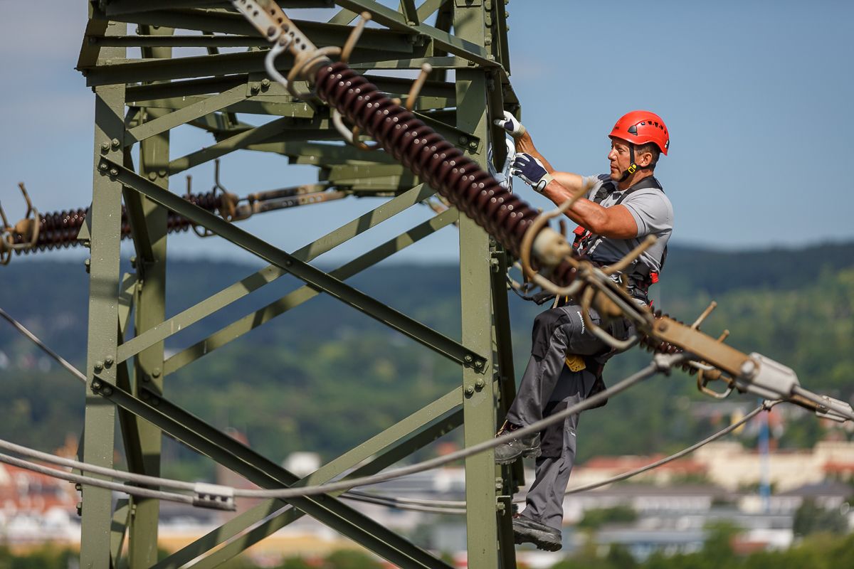 Ein Elektriker arbeitet an einem Hochspannungsmast.