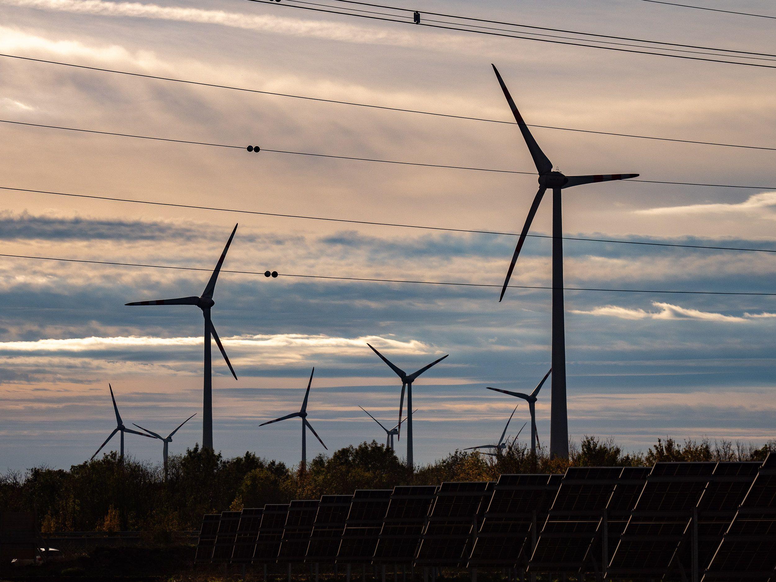 Windkraftanlagen gegen einen dramatischen Himmel im Hintergrund.