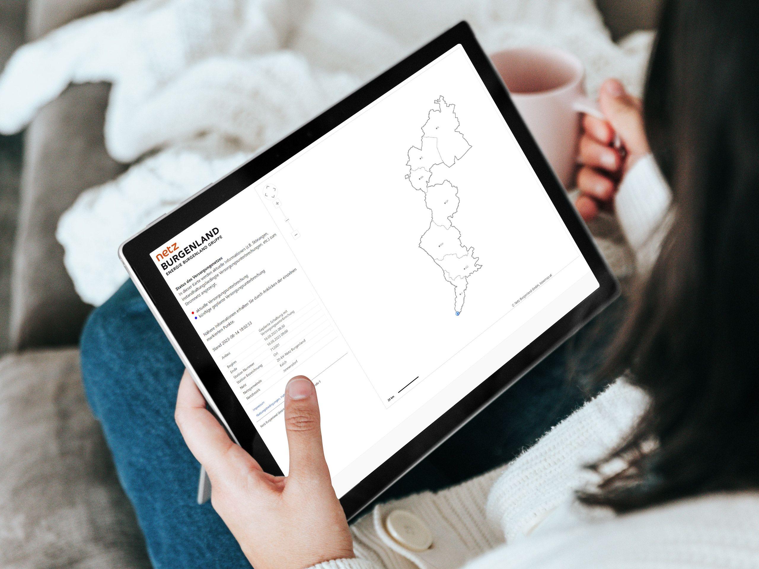 Person hält ein Tablet mit einer geöffneten PDF-Datei zur Versorgungsunterbrechung und Netzausbau in Burgenland.